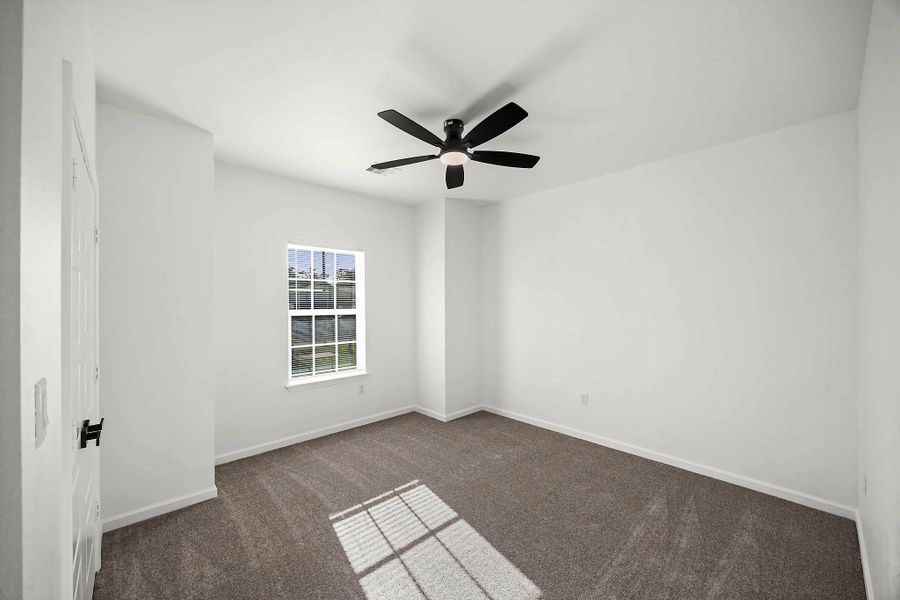 Bright and airy bedroom featuring a large window, plush carpeting, and a sleek ceiling fan for comfort.
