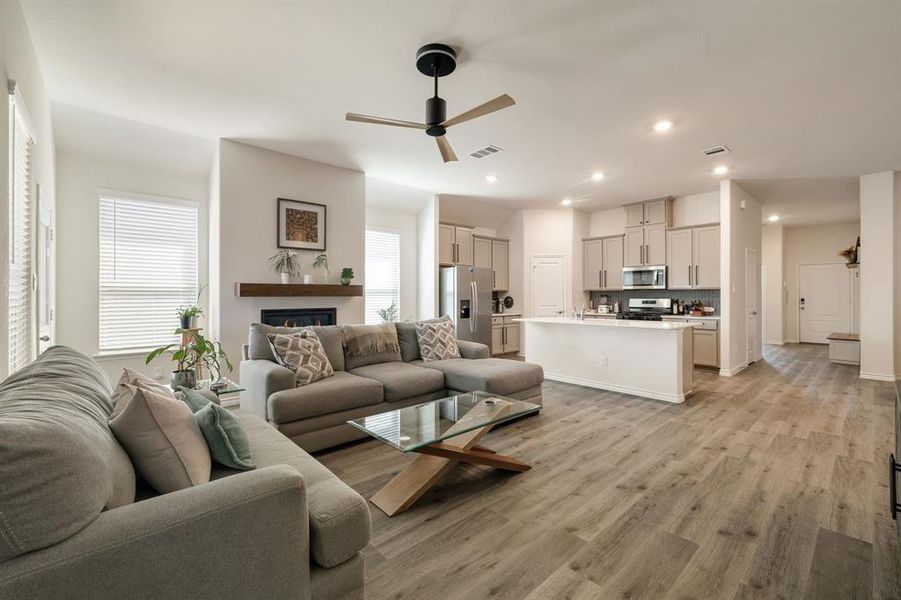 Living room featuring ceiling fan, light wood finished floors, recessed lighting, and a glass covered fireplace Living room featuring ceiling fan, light wood finished floors, recessed lighting, and a glass covered fireplace