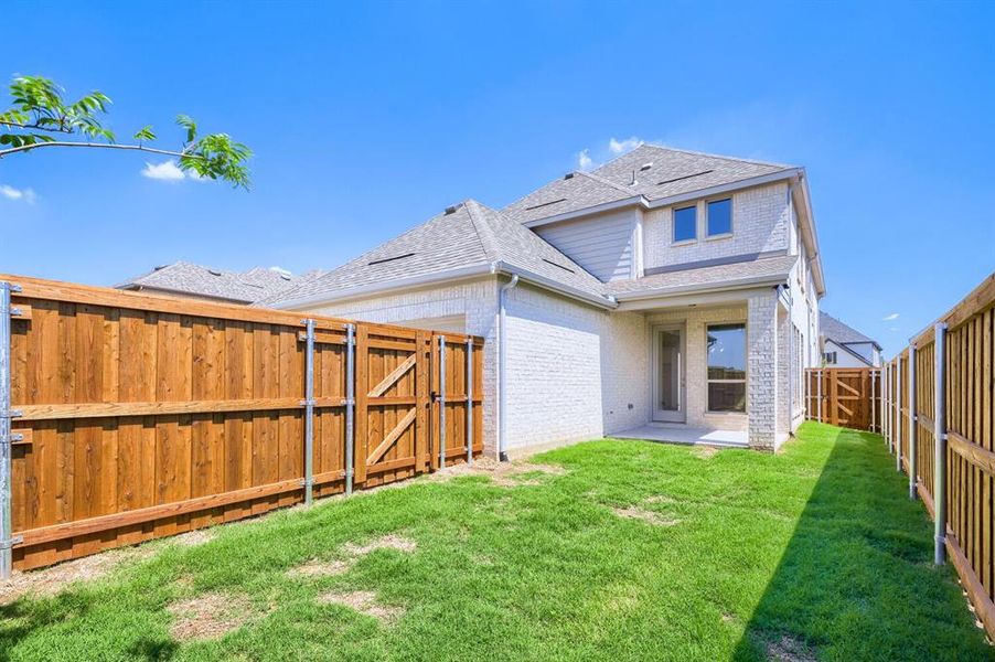 Fenced backyard featuring a manicured lawn, wood fencing with metal posts, and a wood gate