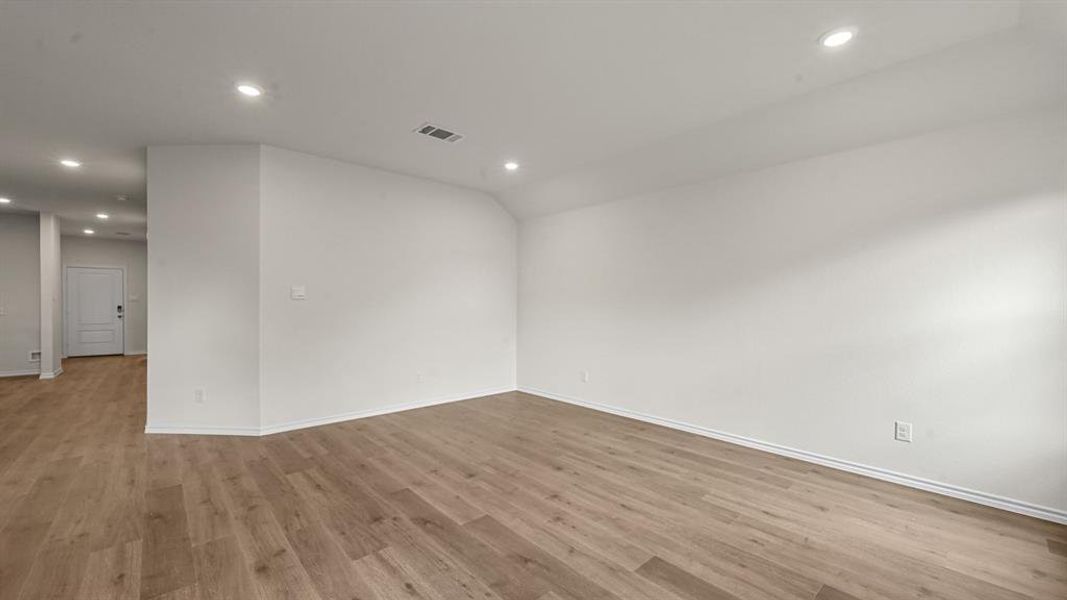 Unfurnished room with recessed lighting, light wood-style floors, and vaulted ceiling