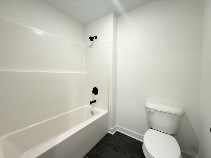 Full bathroom featuring dark tile patterned floors and shower / washtub combination