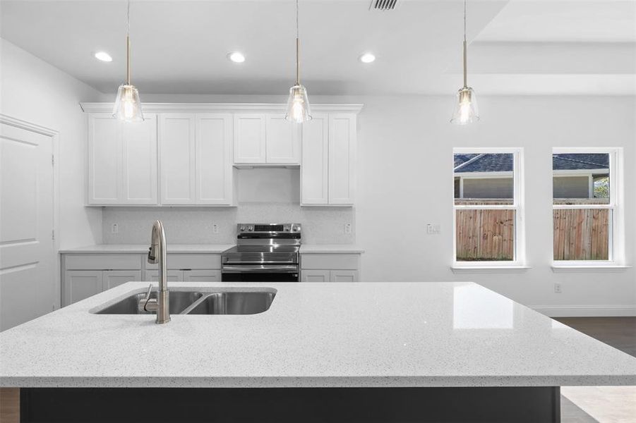 Kitchen featuring stainless steel electric stove, white cabinets, sink, light stone countertops, and decorative light fixtures