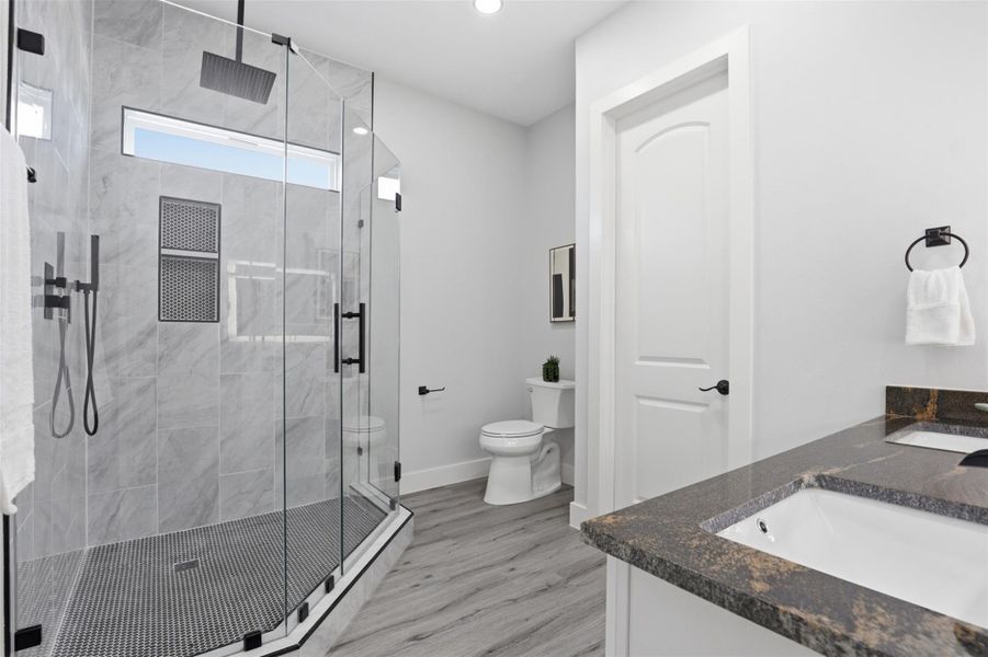Modern bathroom featuring a spacious glass-enclosed shower with a rainfall showerhead and black hardware