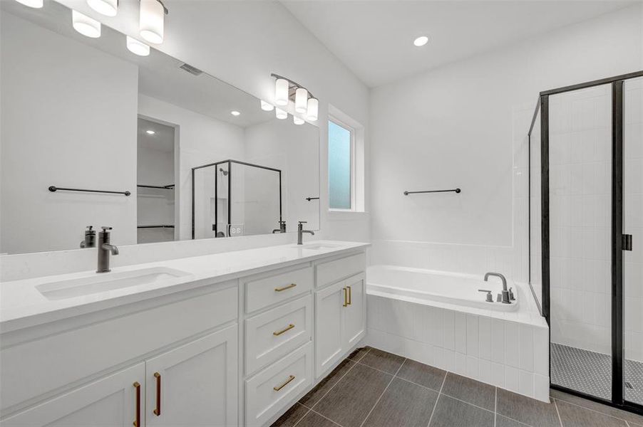 The bathroom features a dual vanity with white cabinetry and gold-toned hardware, a large mirror, and modern light fixtures