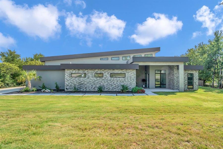 View of front facade featuring stone siding, stucco siding, and a front lawn
