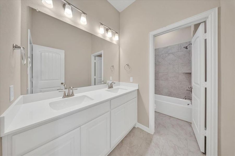 Full bath featuring double vanity, marble finish flooring, and washtub / shower combination Full bath featuring double vanity, marble finish flooring, and washtub / shower combination