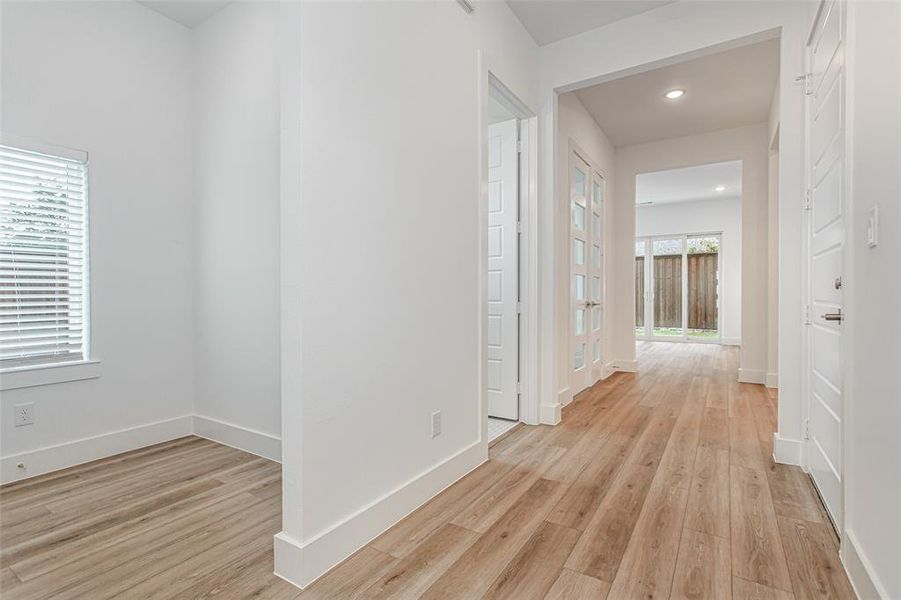 Hallway with light wood-type flooring and recessed lighting