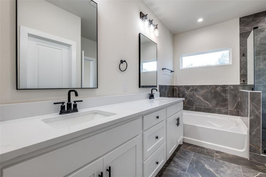 Full bathroom with a bath, double vanity, dark marble finish floors, and a shower