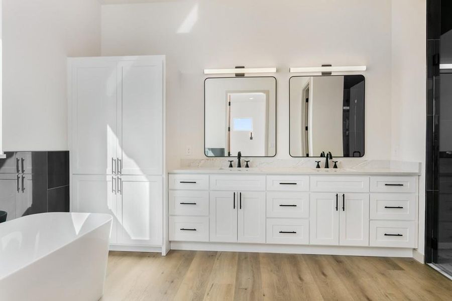 Full bathroom with a freestanding bath, double vanity, light wood-style floors, and a stall shower Full bathroom with a freestanding bath, double vanity, light wood-style floors, and a stall shower