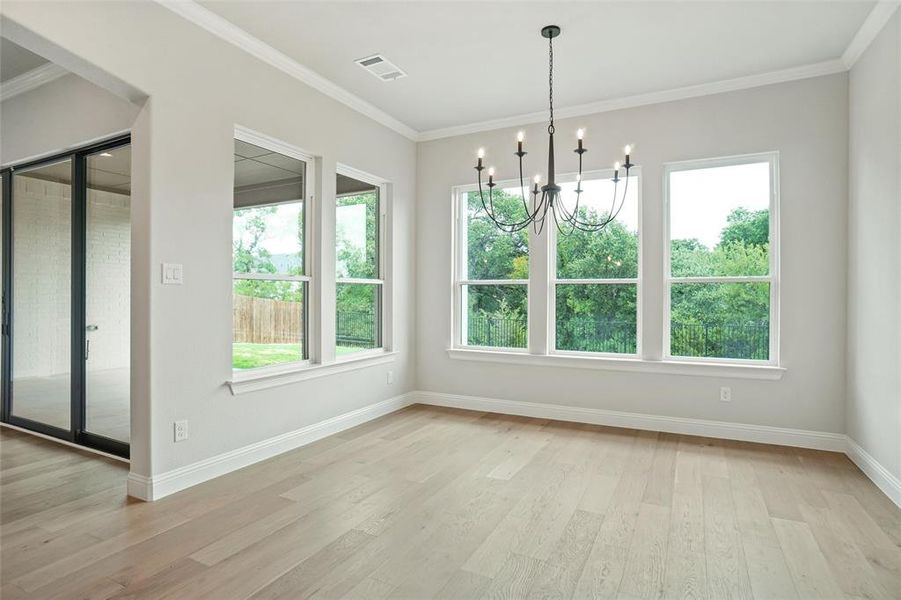 Unfurnished dining area featuring a chandelier, light hardwood / wood-style flooring, and ornamental molding