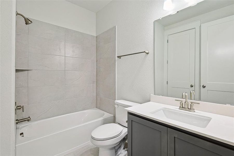 Full bathroom featuring tile patterned floors, toilet, tiled shower / bath, and vanity