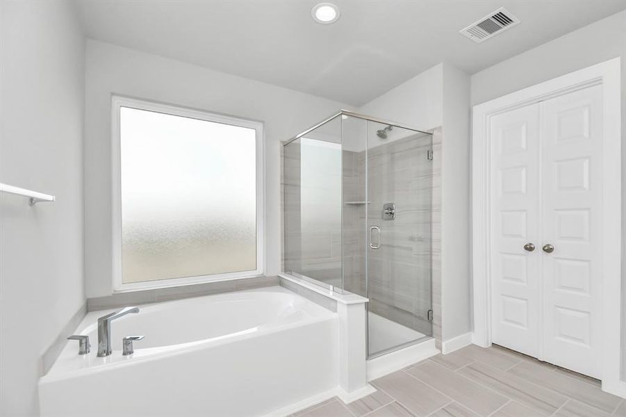 This additional view of the primary bath features a walk-in shower with the tile surround and separate garden tub perfect for soaking after a long day.