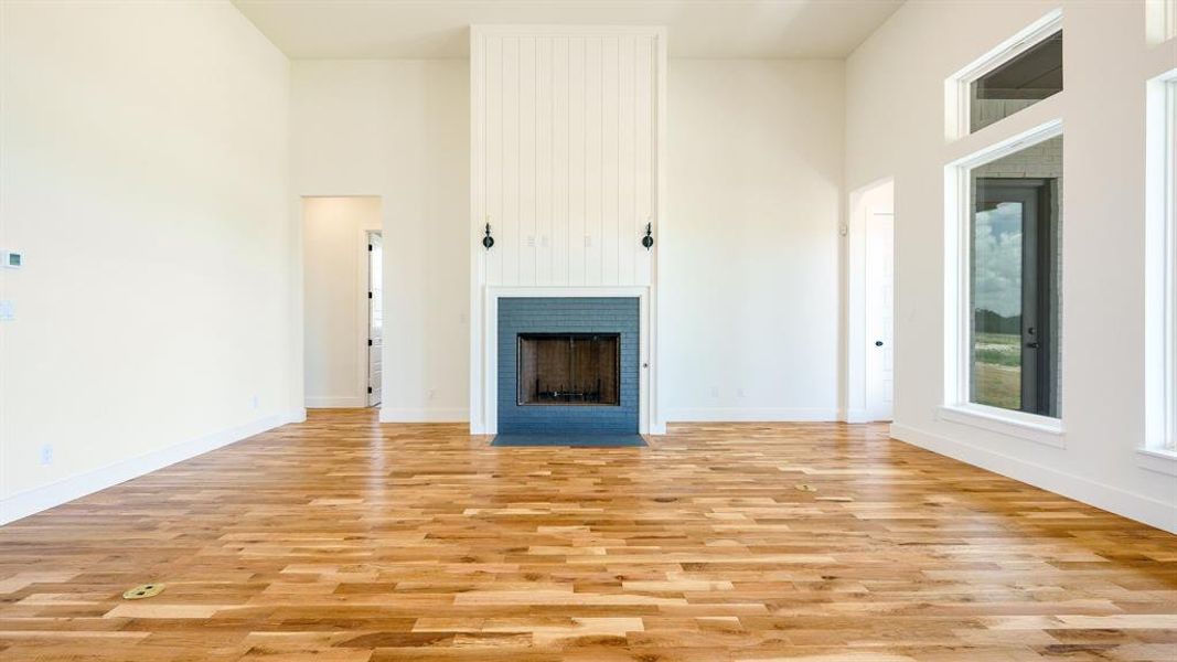 Unfurnished living room with light hardwood / wood-style flooring and a high ceiling