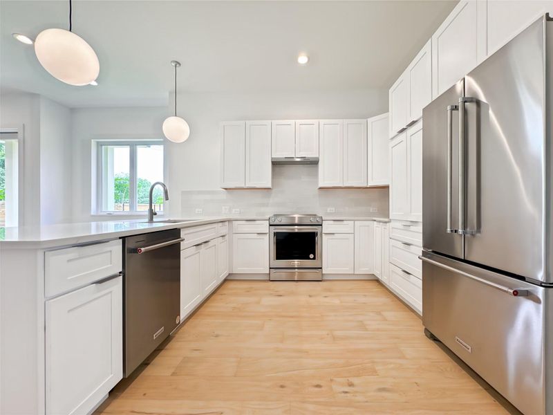 Kitchen featuring appliances with stainless steel finishes, breakfast bar, recessed lighting, and light countertops Kitchen featuring appliances with stainless steel finishes, breakfast bar, recessed lighting, and light countertops