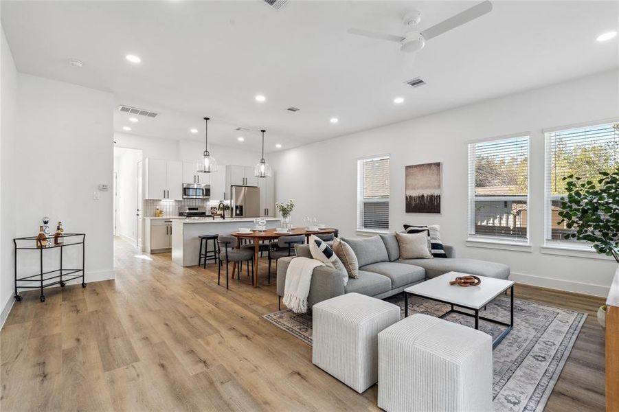 Spacious open-concept layout with seamless flow from the cozy living room to the dining area and modern kitchen, featuring stylish finishes and natural light from multiple windows.