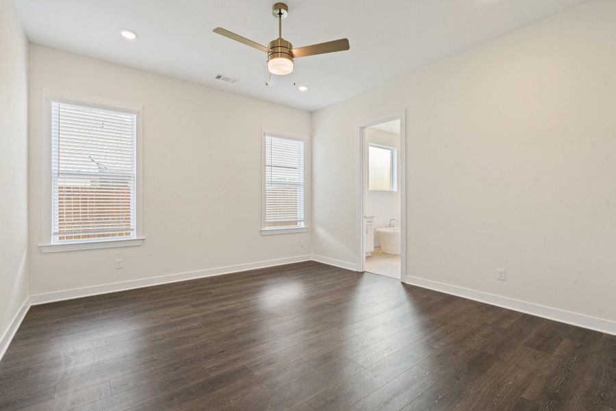 Spacious interior room featuring wood-finish flooring, two windows with blinds, recessed lighting, and a ceiling fan with integrated light Spacious interior room featuring wood-finish flooring, two windows with blinds, recessed lighting, and a ceiling fan with integrated light
