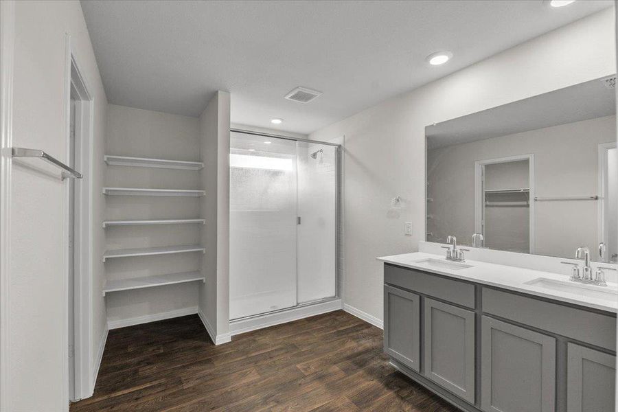 Full bathroom with a walk in closet, double vanity, a shower stall, dark wood-style floors, and recessed lighting