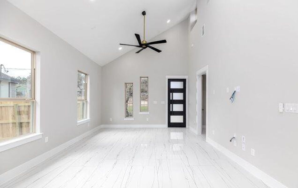 Spacious room featuring a vaulted ceiling and a modern ceiling fan with brass accents