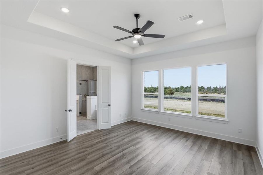 Unfurnished bedroom with ceiling fan, wood finished floors, recessed lighting, and a tray ceiling