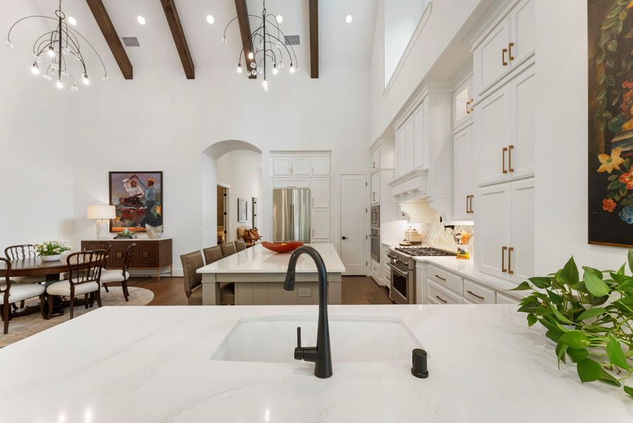 Elevated ceiling height, exposed beams, and a generous island give the kitchen a dramatic sense of scale. The space feels open and inviting while still offering abundant cabinetry and storage.