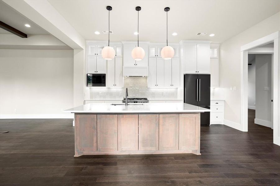 Kitchen featuring dark hardwood / wood-style floors, white cabinets, and a kitchen island with sink