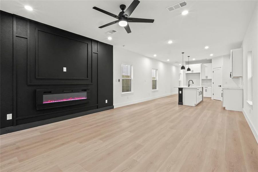 Unfurnished living room featuring ceiling fan, recessed lighting, light wood finished floors, and a fireplace Unfurnished living room featuring ceiling fan, recessed lighting, light wood finished floors, and a fireplace