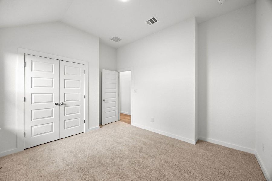 An inviting room boasts soft carpet underfoot and pristine white walls ready for personalization.