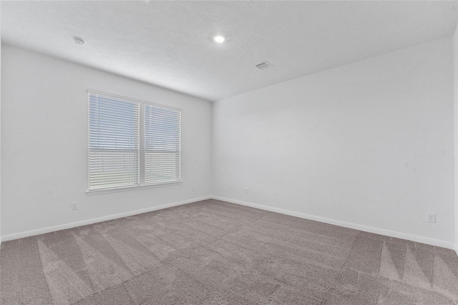 Come and unwind after a long day in this magnificent primary suite! This spacious room features plush carpet flooring, neutral paint, high ceilings and large windows with privacy blinds.