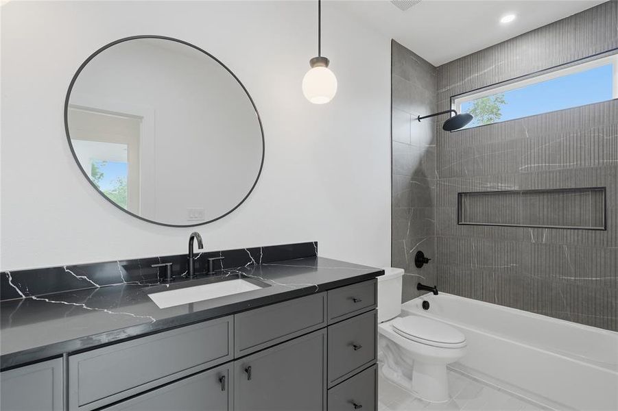 Contemporary bathroom featuring a dark vanity with a patterned countertop, a circular mirror, and a wall-mounted globe light fixture Contemporary bathroom featuring a dark vanity with a patterned countertop, a circular mirror, and a wall-mounted globe light fixture