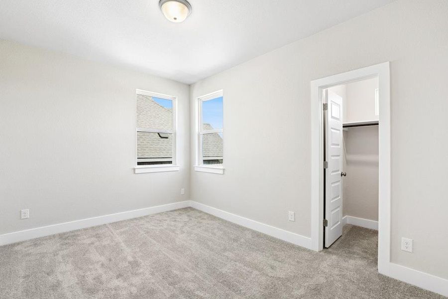 Unfurnished bedroom with a walk in closet and light carpet Unfurnished bedroom with a walk in closet and light carpet