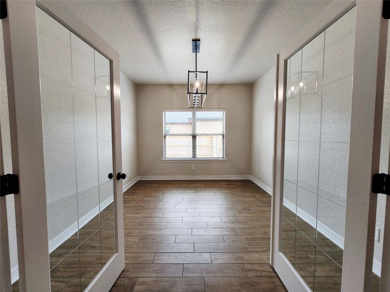 French doors open to a spacious room featuring rich wood flooring and abundant light. French doors open to a spacious room featuring rich wood flooring and abundant light.