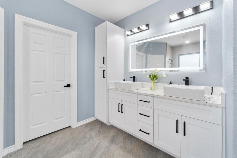 Bathroom featuring double vanity and baseboards Bathroom featuring double vanity and baseboards