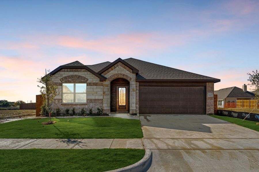 Single-story brick and stone home with two-car garage, arched entry door, and green front lawn.