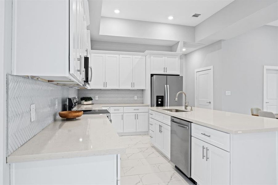 Expansive kitchen with plenty of cabinetry, a large island with a sink, and modern finishes