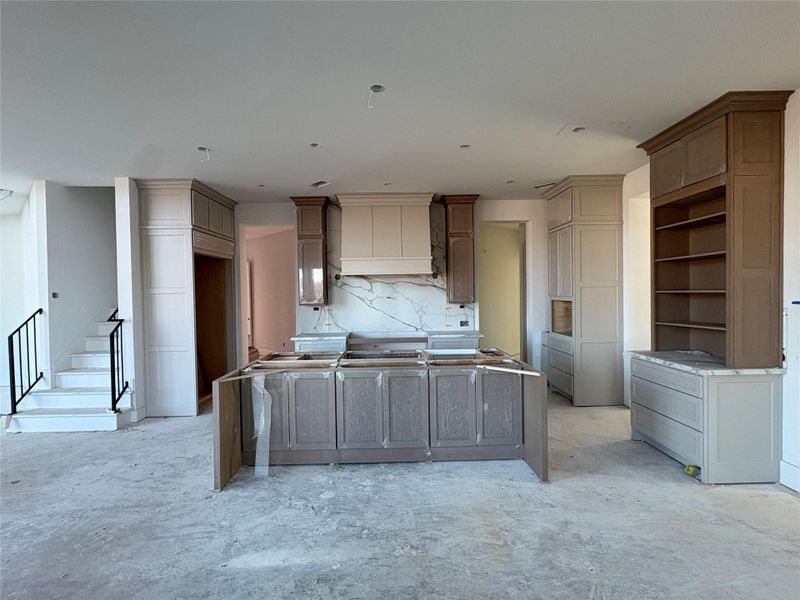 Chef's kitchen with large island. Floors will be wide plank engineered wood. Photo as of 3.19.26 Chef's kitchen with large island. Floors will be wide plank engineered wood. Photo as of 3.19.26