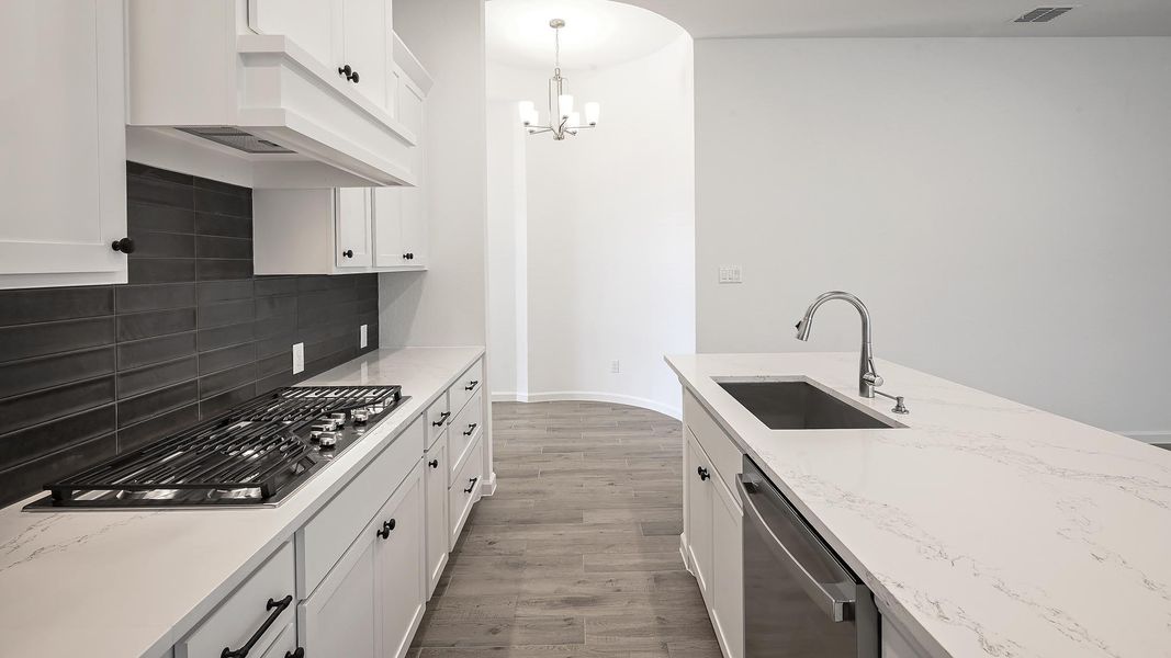 Kitchen with white cabinetry, light wood-type flooring, appliances with stainless steel finishes, and light stone countertops Kitchen with white cabinetry, light wood-type flooring, appliances with stainless steel finishes, and light stone countertops
