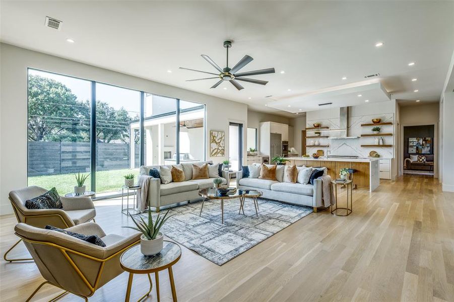 Living room featuring a healthy amount of sunlight, ceiling fan, and light hardwood / wood-style flooring