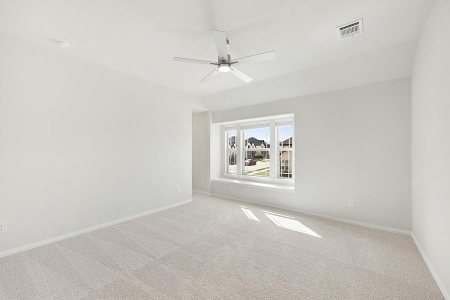 Empty bedroom with vaulted ceiling, ceiling fan, carpet flooring, and large window with neighborhood view