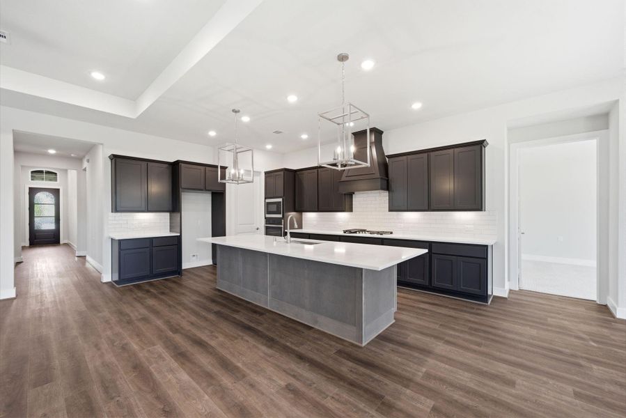 Chef’s kitchen featuring a large island, quartz countertops, and stylish cabinetry with designer lighting.