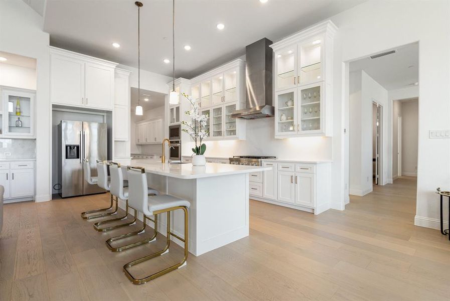 Kitchen featuring glass insert cabinets, a kitchen bar, appliances with stainless steel finishes, white cabinetry, and recessed lighting