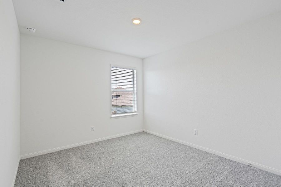 Clean lines and soft carpeting define this versatile, neutral-toned secondary bedroom.