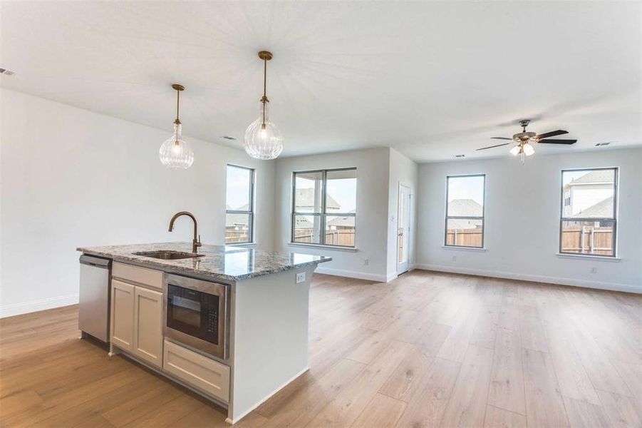 Kitchen with dishwasher, built in microwave, a sink, a center island with sink, and light wood finished floors