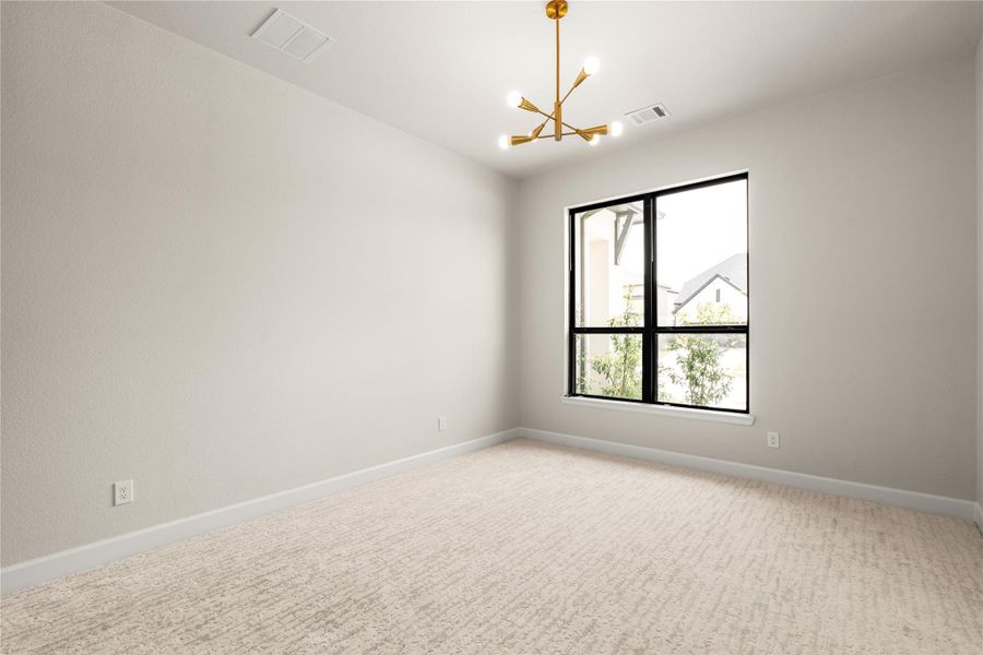 Bright and airy secondary bedroom featuring a modern light fixture and a large window that invites natural light, complemented by soft carpet flooring and neutral walls.