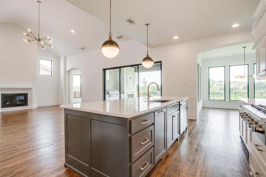 Kitchen with dark hardwood / wood-style flooring, a kitchen island with sink, pendant lighting, a chandelier, and sink