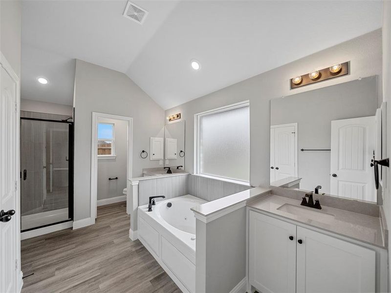 Bathroom featuring a tub with jets, visible vents, a shower stall, vaulted ceiling, and toilet