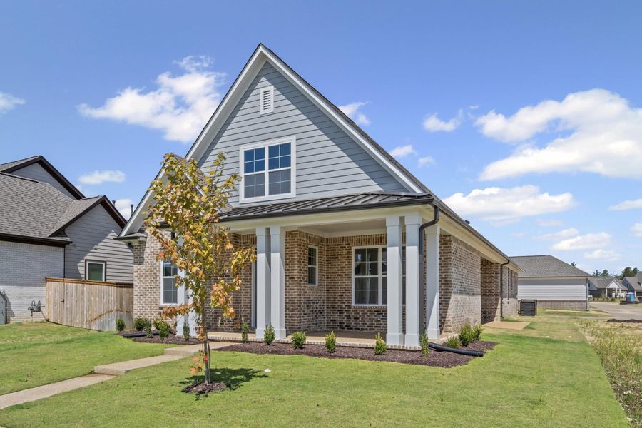 Traditional home with brick siding, a standing seam roof, a metal roof, and covered porch Traditional home with brick siding, a standing seam roof, a metal roof, and covered porch