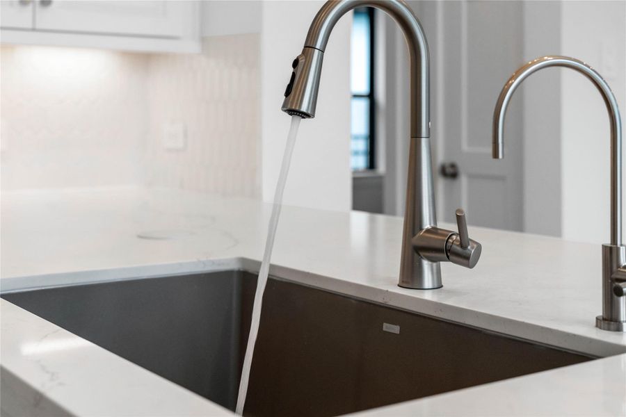 The Moen Sleek stainless steel kitchen faucet offers versatility and contemporary design, complemented by a convenient separate filtered water dispenser faucet.