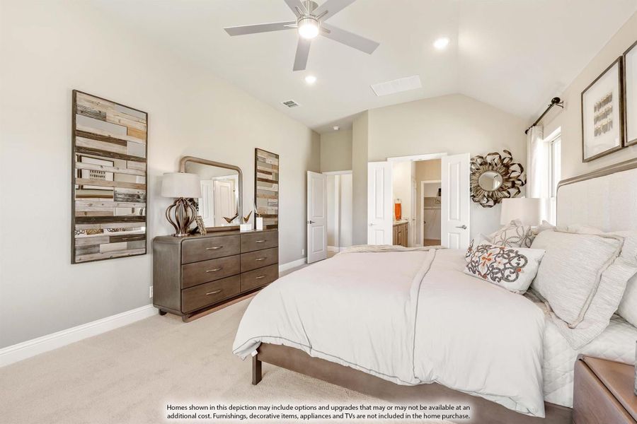 Master bedroom with vaulted ceiling, ceiling fan, carpet flooring, and wood dresser with open ensuite bathroom door.