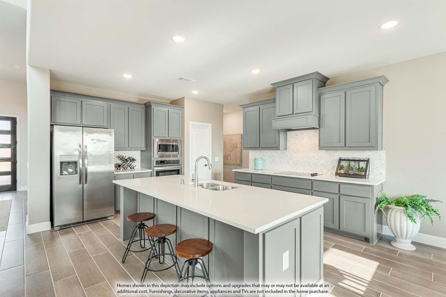 Kitchen with gray cabinets, large island with sink, white countertops, and stainless steel appliances