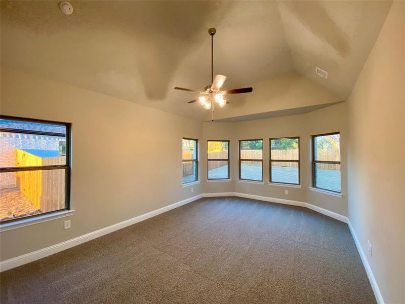 Large master bedroom offers vaulted ceiling, bay window, and ceiling fan